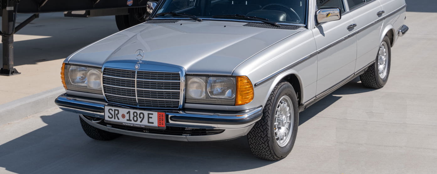 A Mercedes 123 in a sunny car park