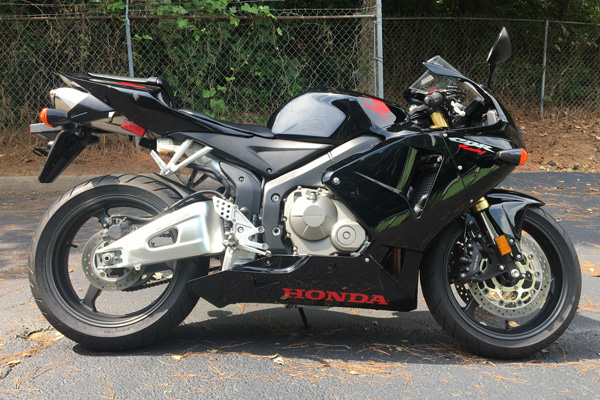 A black 2006 Honda CBR600RR standing on tarmac in the sun