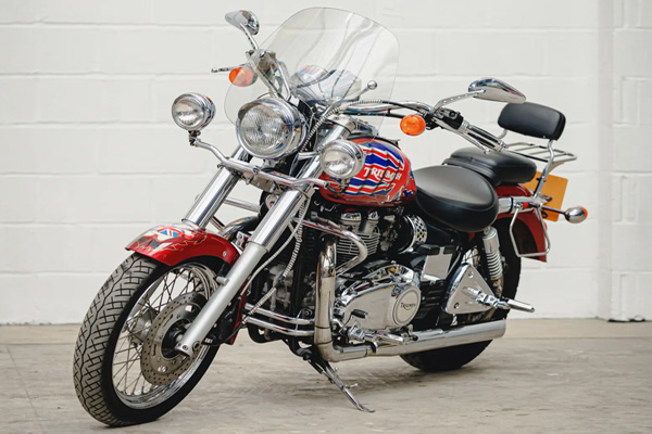 Red Triumph Bonneville viewed against a white breezeblock garage wall
