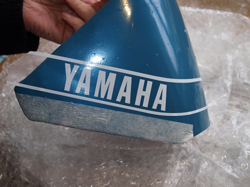 Man holding the petrol tank cover with Yamaha decal attached