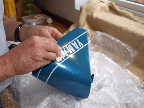 Man wiping tissue over the decal sticker on the petrol tank cover