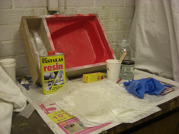 Mould, resin, mixing pots, latex gloves, and other items sitting on newspaper