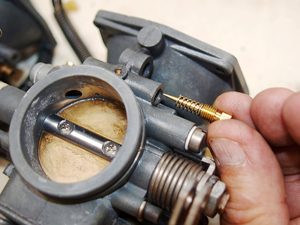 Holding a screw to the passage behind the air and mixture screws