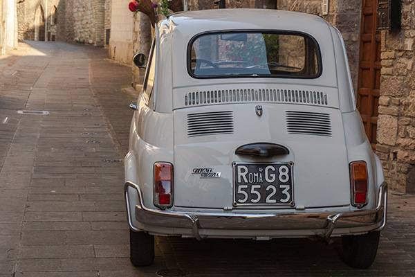 White 1968 to 1975 Fiat 500L On Old Cobbled Assisi Stone Flagged Lane And Doors