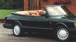 header-black-saab-900-convertible-beside-an-old-home-with-lots-of-potted-flowers