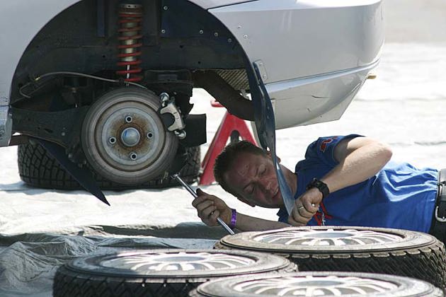 A mechanic lying on the ground working on a car wheel