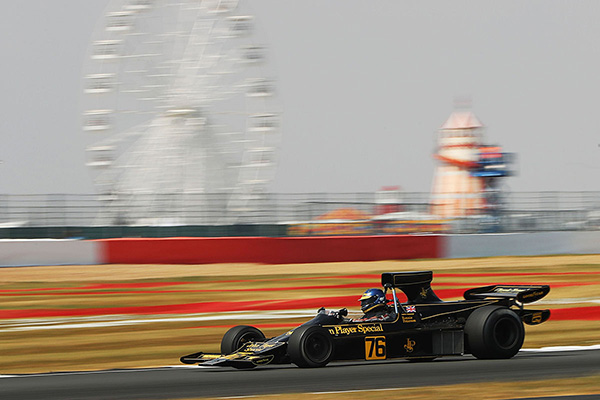 Lotus 761 John Player Special Formula 1 Racing Car On A Track Blurred Back Drop Of A Ferris Wheel And Helter Skelter