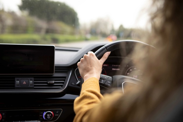 A woman in a yellow jumper driving a car