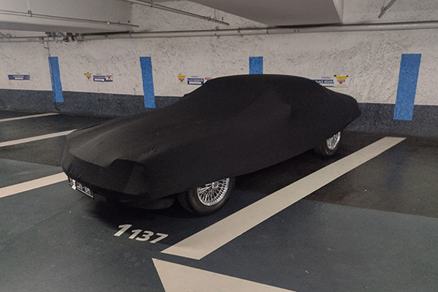 covered-car-with-spoked-wheels-in-car-park