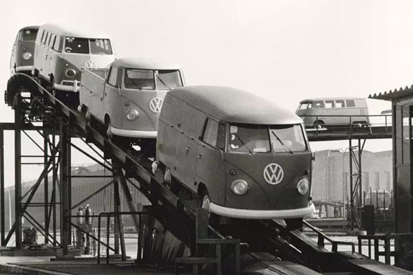 Monochrome photo of Different Styles Of Volkswagen Transporters On A Conveyor Belt with a Ramp