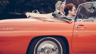 A couple in a red open top car