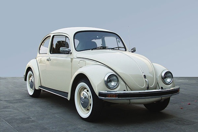 A cream VW Beetle against a blue background
