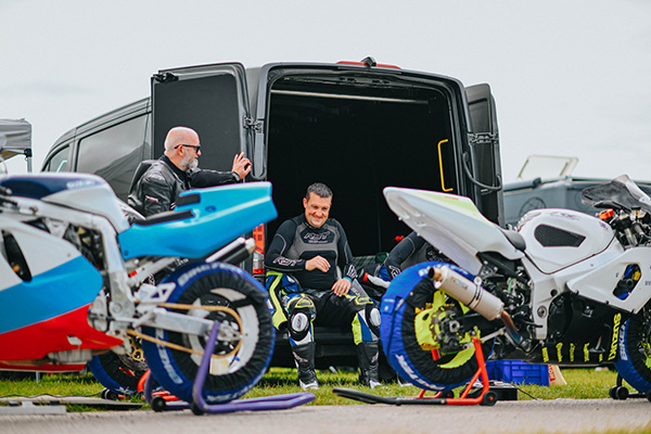 Two Racing Motorbikes On Yoke Stands, in front of the back doors of a van photo Courtesy Classic Bike Track day
