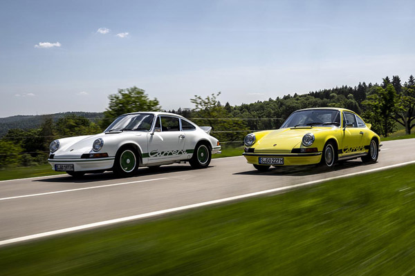 A white and a yellow 1970'S Porsche 911 Carrera 2.7 RS driven on road