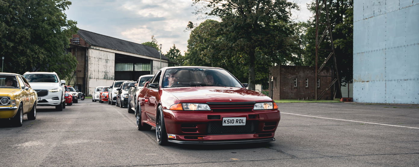 A Red classic car driving on an industrial estate