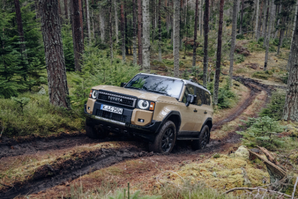 Beige 2023 Toyota Land Cruiser Amazon driving on a dirt track through a forest