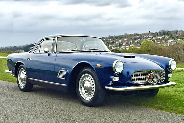 Maserati 3500 Gti Courtesy Southwood Car Company on grass verge with leafy housing backdrop