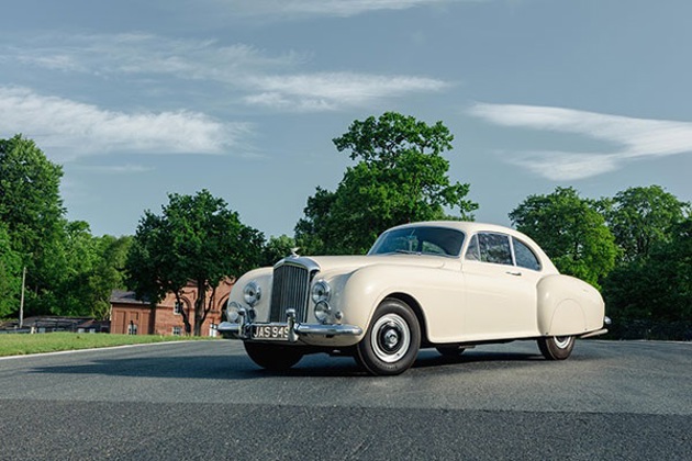 A white Bentley R type driving on tarmac
