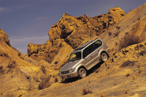 Silver 1996 2002 Toyota Land Cruiser Colorado 90 Series driving through rocky, hilly, desert
