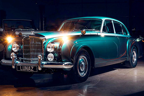 A Pearlescent Tourmaline Green Bentley Continental Ev being Charged in a showroom