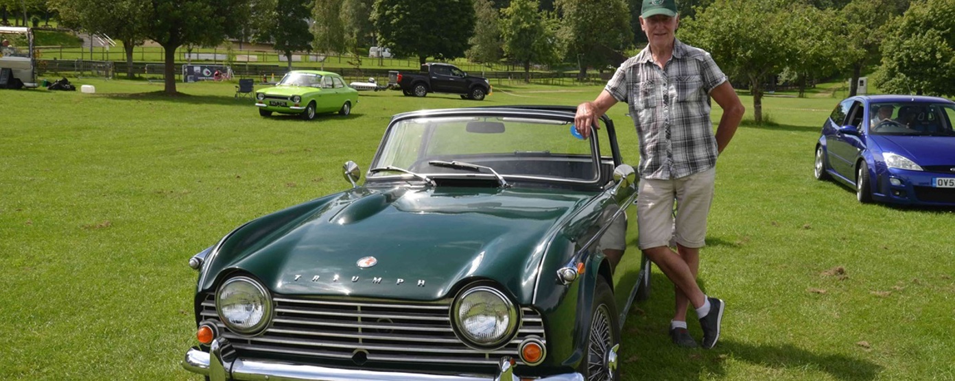 A Coffee and Chrome attendee posing with his green Triumph classic car